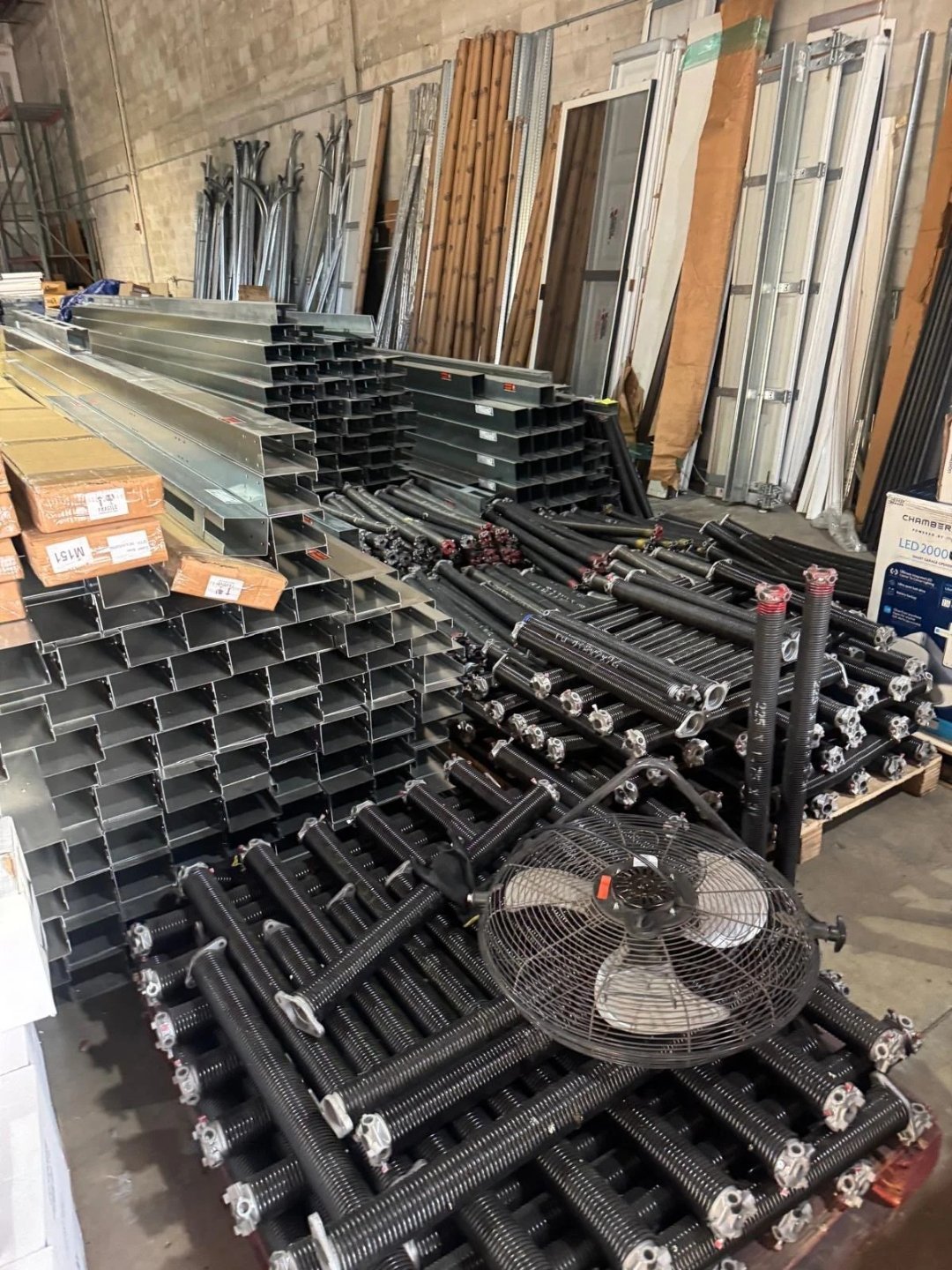 Stacks of garage door track sections and hardware staged for an installation