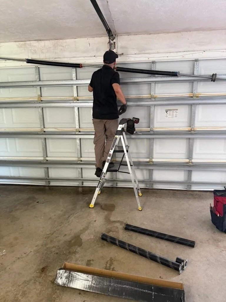 Technician on a ladder at the torsion bar with old track pieces laid on the floor